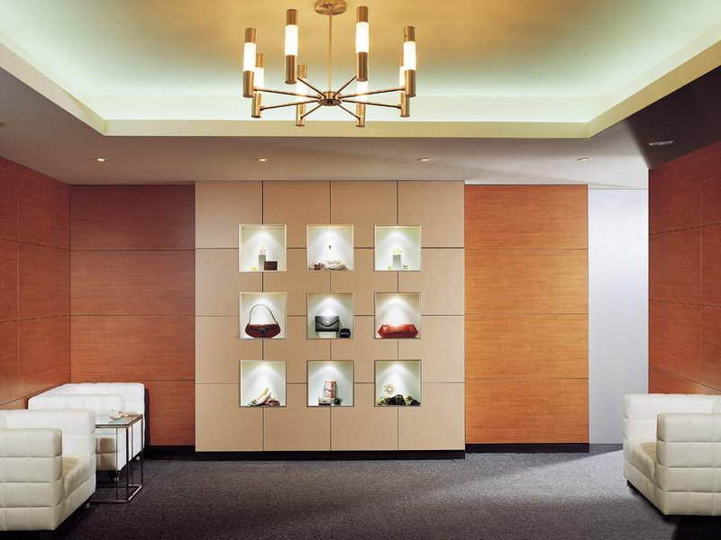 Retail lounge with warm wall panels, illuminated display niches and a recessed ceiling