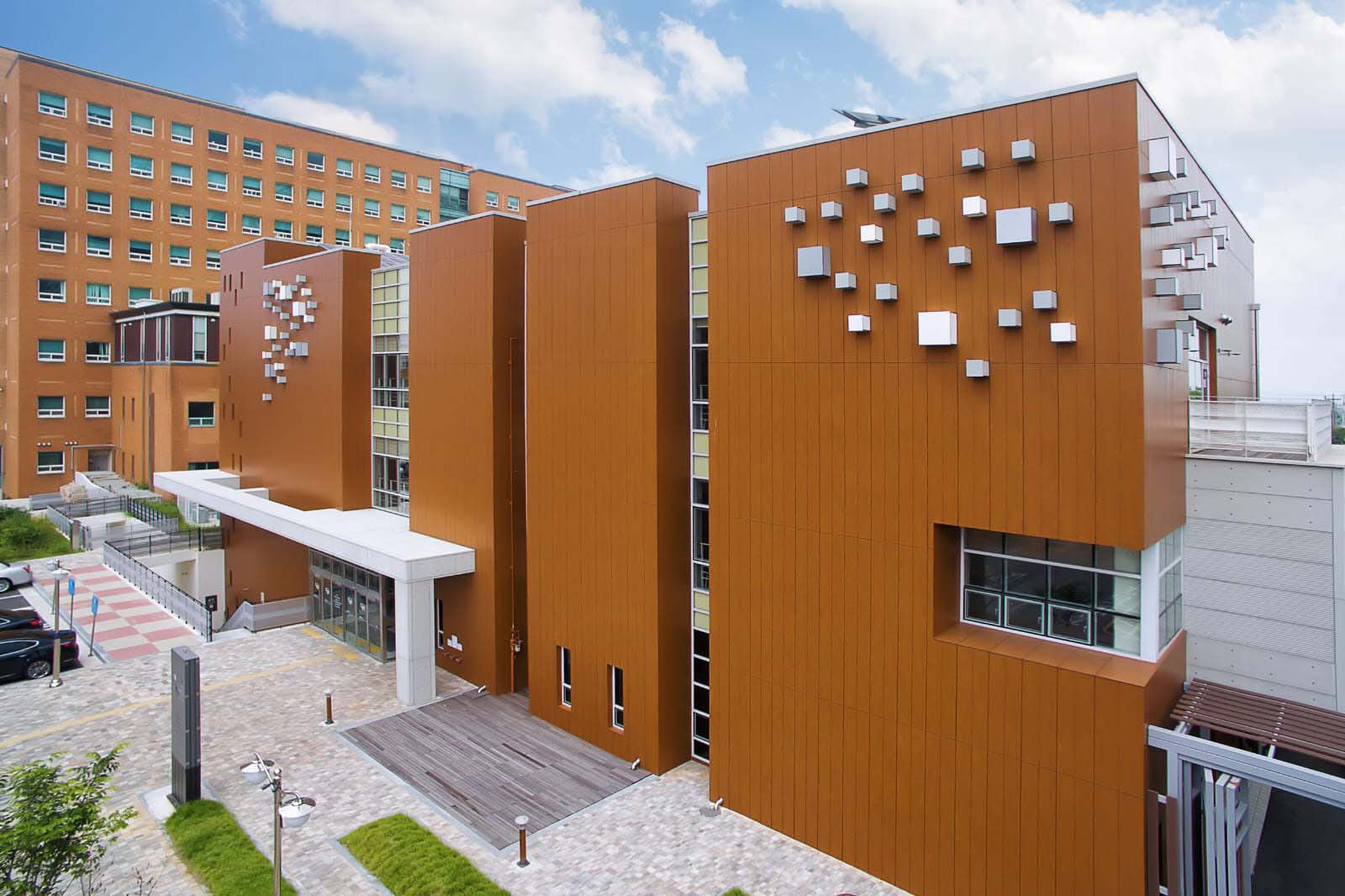 Education building with warm-colored exterior panels, repeated windows and projecting white elements.