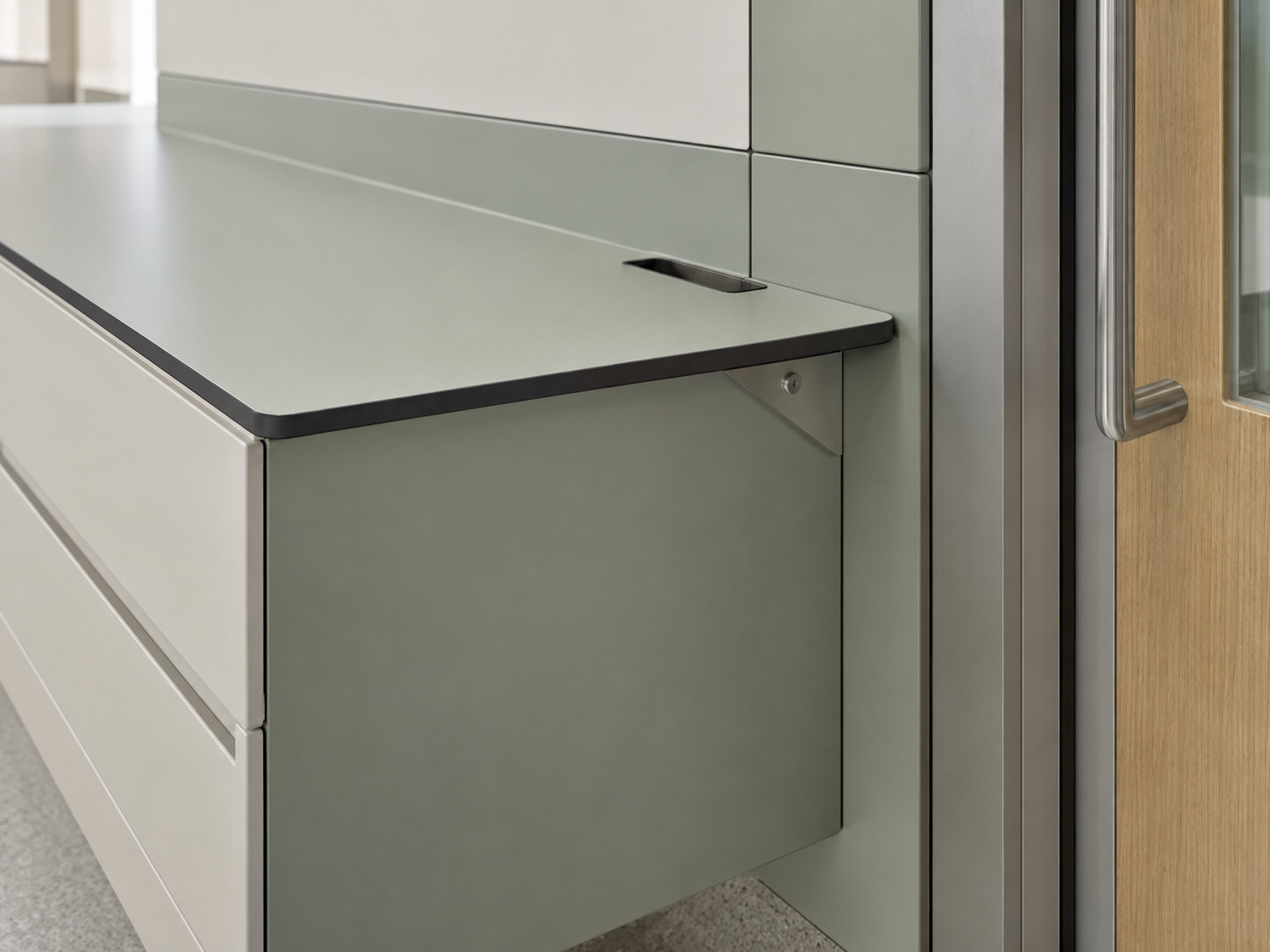 Illustrative close view of a thin worktop with an exposed dark core, rounded corner, machined opening and supporting bracket beside a door.