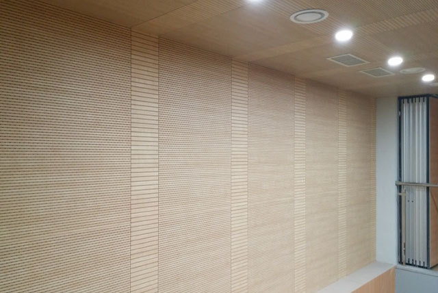 Light grooved wall panels meeting a matching ceiling with recessed lights, circular diffusers and square service grilles.