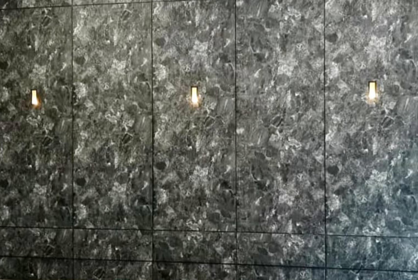 Dark patterned wall divided by vertical and horizontal joints with three small wall lights.