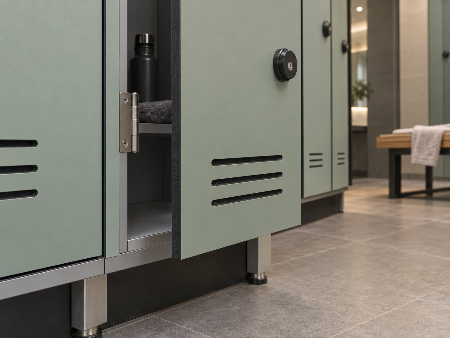Open sage locker door showing a dark core edge, metal hinge, round lock, horizontal ventilation slots and adjustable supports above the tiled floor.