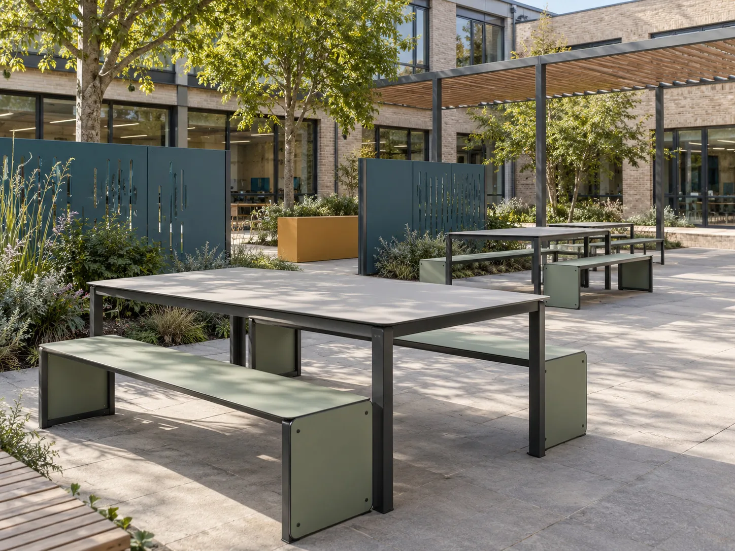 Outdoor tables and sage benches with teal screen panels, planting and a canopy beside a courtyard building.