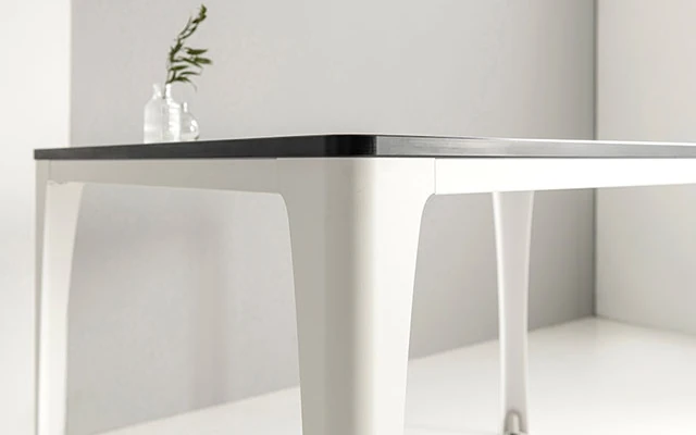 Slim tabletop and shaped panel legs in a light workspace.