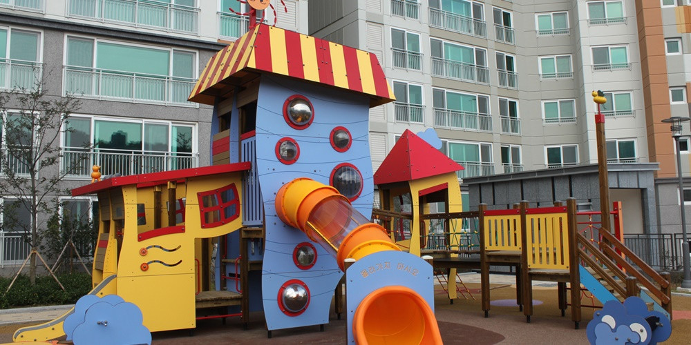 Outdoor play tower with coloured side panels and circular openings beside a tube slide