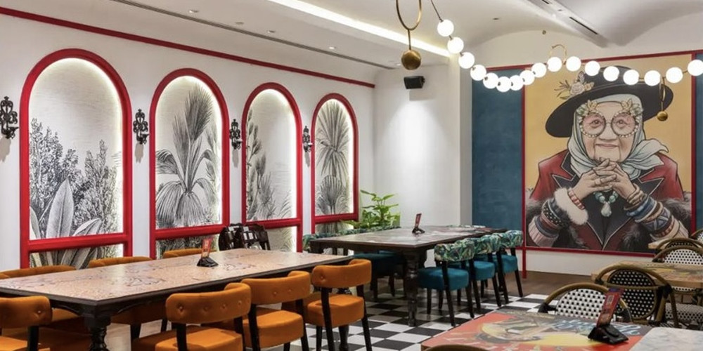 Restaurant tables beside orange chairs and framed botanical wall images