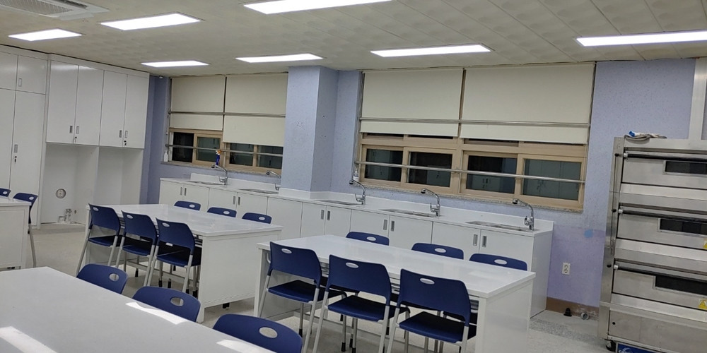 School laboratory with pale worktops, blue chairs, storage cabinets and sinks along the windows